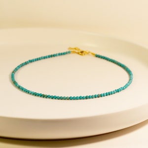 Puede incluir: Un collar de cuentas turquesa con cierre dorado.