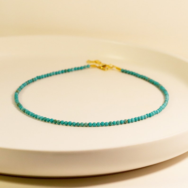 Puede incluir: Un collar de cuentas turquesa con cierre dorado.