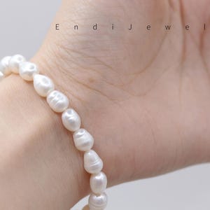 May include: A white pearl bracelet with irregular shaped pearls. The bracelet is strung together and is worn on a wrist. The text "Endi Jewels" is visible in the image.