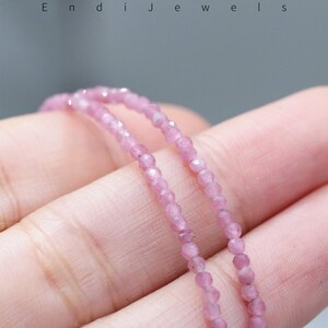 May include: Close-up of a delicate pink gemstone bead necklace. The beads are small and faceted, strung together to create a subtle sparkle. The necklace is held in a hand, with the brand name "Endi Jewels" visible at the top.