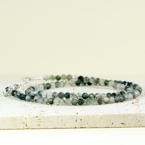Puede incluir: Un brazalete de doble cadena hecho con cuentas de ágata verde y transparente. El brazalete tiene un cierre plateado.