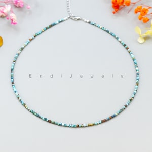 May include: A delicate turquoise and brown beaded necklace with a silver clasp. The necklace is on a gray background with the text "Endi Jewels" printed in black.