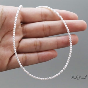 May include: A delicate necklace composed of a single strand of small, uniform white pearls. The necklace is circular in shape and features a subtle lustre. The text EndiJewels is visible in the bottom right corner of the image.