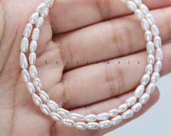 Könnte beinhalten: Nahaufnahme einer doppelten Kette aus weißen, oval geformten Perlen. Die Perlen sind aufgefädelt und bilden eine zarte Halskette. Das Bild enthält den Text "Endi jewels".