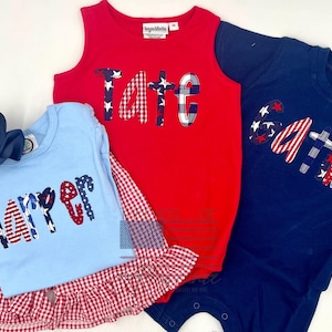 Puede incluir: Tres conjuntos infantiles en rojo, azul claro y azul marino. La camiseta sin mangas roja dice "TATE", la camisa azul claro "HARPER" y el body azul marino "GATTIN". Cada nombre está en un diseño de patchwork patriótico.