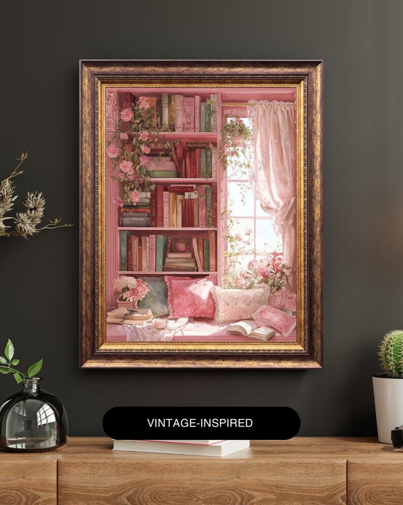 May include: A framed painting of a cozy reading nook. The artwork depicts a pink bookshelf filled with books, a window with sheer curtains, and a window seat with pillows. Roses and other flowers adorn the scene. The frame is gold. Text on the bottom reads "VINTAGE-INSPIRED".