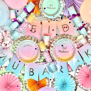 Op de afbeelding: Een kleurrijke Eid Mubarak feestbenodigdhedenset met pastelroze, blauwe en gele papieren borden, papieren waaiers en papieren banners. De set bevat een verscheidenheid aan decoraties met gouden glitteraccenten en de tekst "Eid Mubarak".