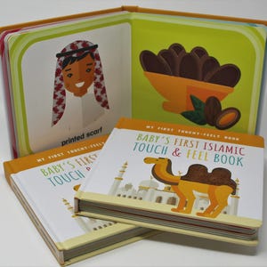 May include: A children's book titled "Baby's First Islamic Touch & Feel Book" with illustrations of a camel and a mosque. The open book shows images of a person wearing a printed scarf and dates in a bowl. The book has a yellow and white cover.