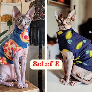May include: A set of two sleeveless shirts for a Sphynx cat. One shirt is blue with a pizza slice pattern, and the other is dark blue with a yellow lemon pattern. Both shirts feature a high neck design. The text Set of 2 is visible in the center.