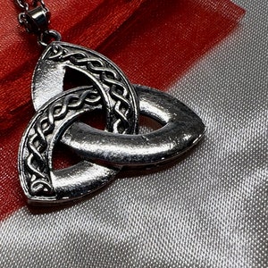 Peut inclure: Un collier avec un pendentif en argent en forme de nœud celtique. Le pendentif est un nœud trinitaire, symbole d'amour, de foi et d'espoir.