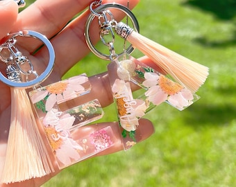 Sleutelhanger van hars met droge bloem en kwastje, inclusief sleutelhanger. Voeg een naam toe zonder extra kosten.