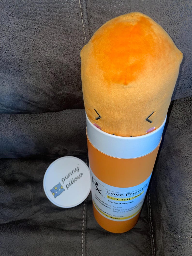 May include: A plush orange pill shaped pillow in a pill bottle container. The bottle is labeled "Love Pharma" and has a prescription number "RX# C10H12N2O".