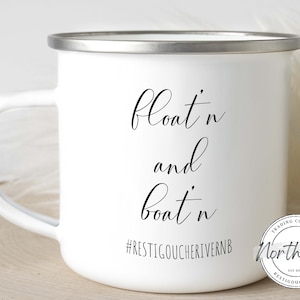 May include: White enamel mug with a silver rim and handle. The mug features the words "Float'n and Boat'n" in a stylish script, along with the hashtag #RESTIGOUCHERIVERNB and a circular logo. A perfect gift for outdoor enthusiasts.