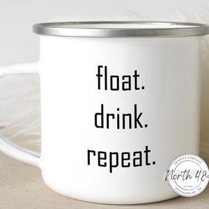 May include: White enamel mug with a silver rim and handle. The mug features the words "float. drink. repeat." in black, block letters. A circular logo with the text "North 48" is on the side.