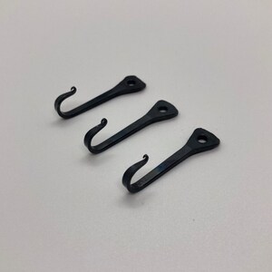 May include: Three black metal hooks with a simple design. Each hook has a pointed end and a curved hook.