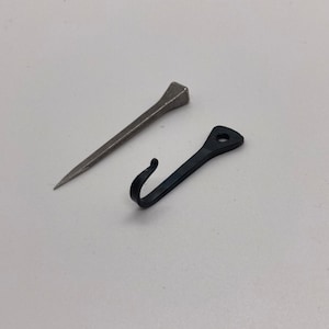 May include: A silver horseshoe nail and a black metal hook. Both are small and would be used for crafting or DIY projects.