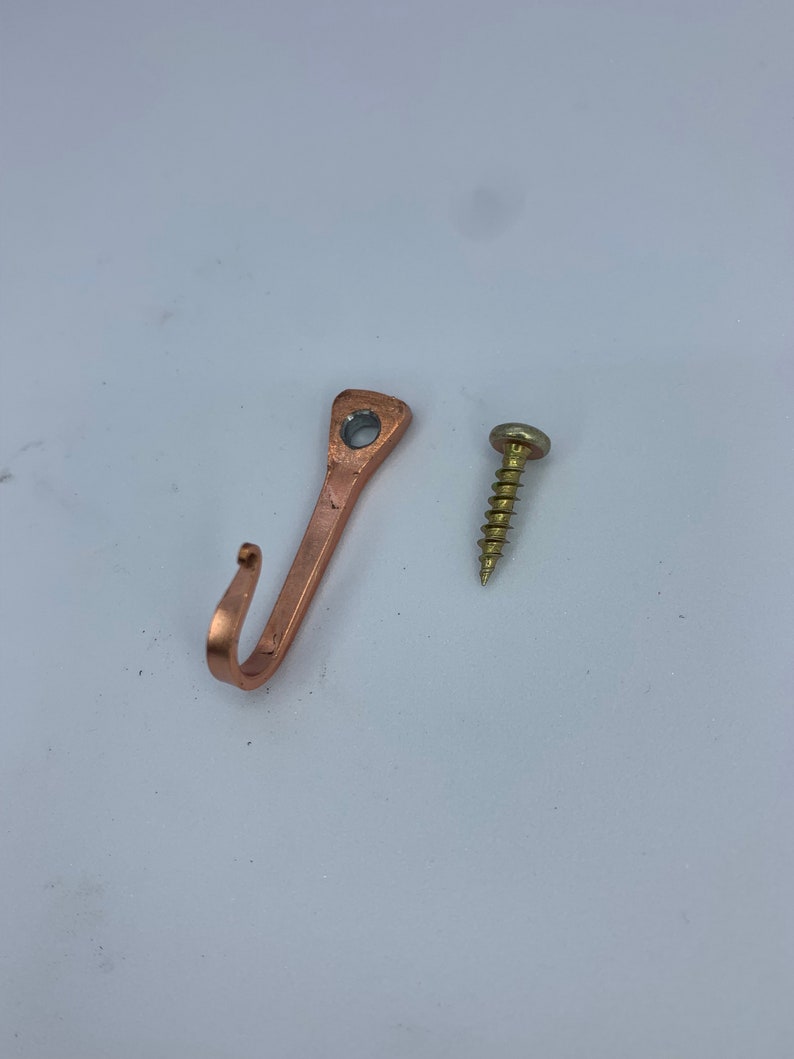 May include: A copper-colored hook with a screw for hanging items on a wall.