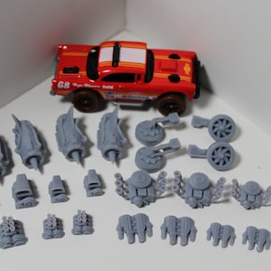 May include: A set of 19 gray 3D printed car engine parts for model building. The parts include a variety of engine blocks, exhaust manifolds, and other components.