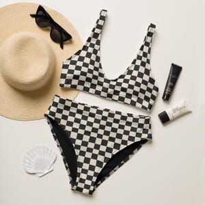 May include: Black and white checkered bikini top and bottom. The bikini top has a scoop neck and the bikini bottom has high-waisted legs.
