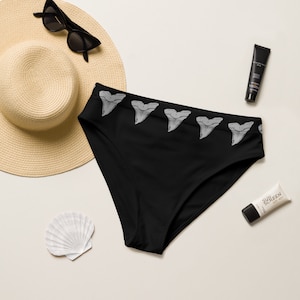 May include: Black bikini bottoms with a row of white shark teeth along the waistband.