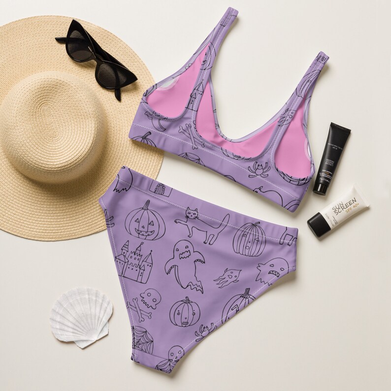 May include: Purple and pink Halloween-themed bikini with a black and white print of pumpkins, ghosts, and other spooky characters.
