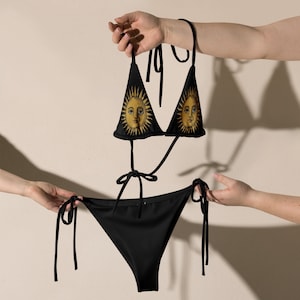 May include: Black bikini with a sun and face print on the top and a solid black bottom.