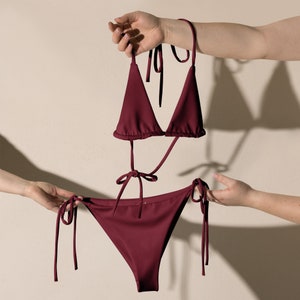 May include: A burgundy bikini top and bottom with adjustable straps. The top is a triangle style and the bottom is a cheeky cut.