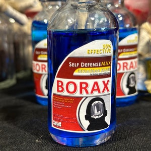 May include: A blue glass bottle with a red and white label that reads "Self DefenseMax Leviathan Killer Borax 90% Effective". The label also includes a black and white illustration of a creature with sharp teeth.