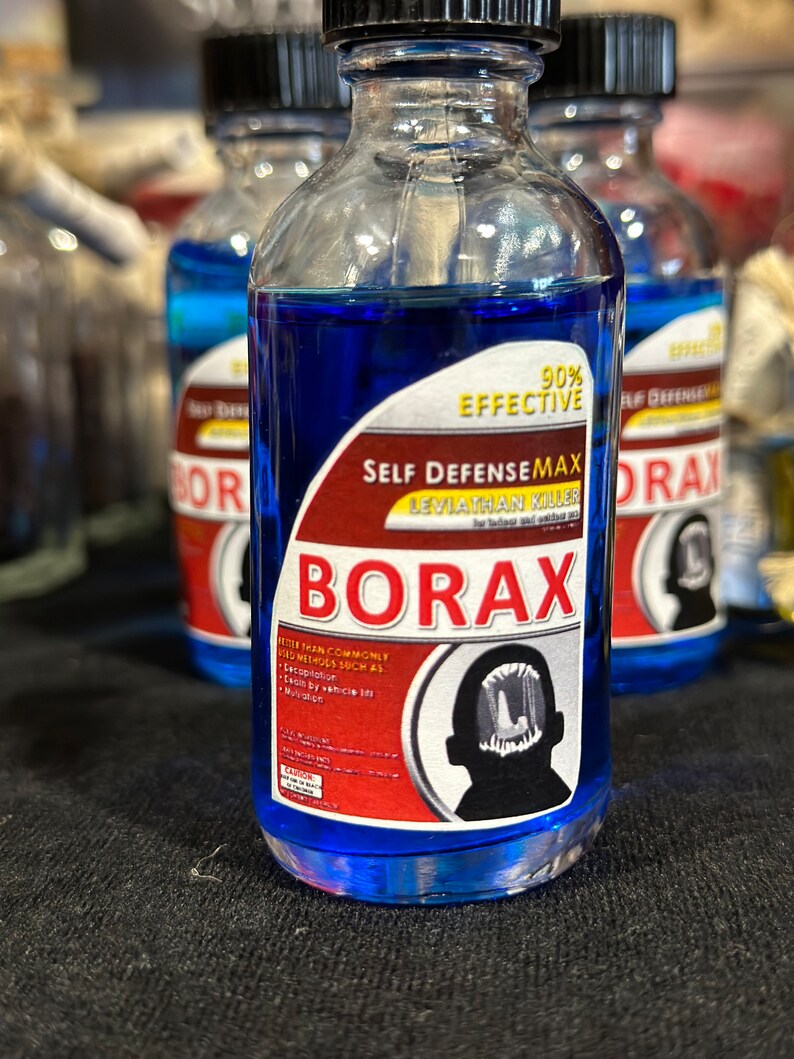 May include: A blue glass bottle with a red and white label that reads "Self DefenseMax Leviathan Killer Borax 90% Effective". The label also includes a black and white illustration of a creature with sharp teeth.