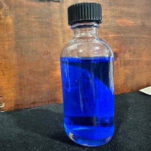 May include: A clear glass bottle with a black screw-on cap filled with a bright blue liquid.