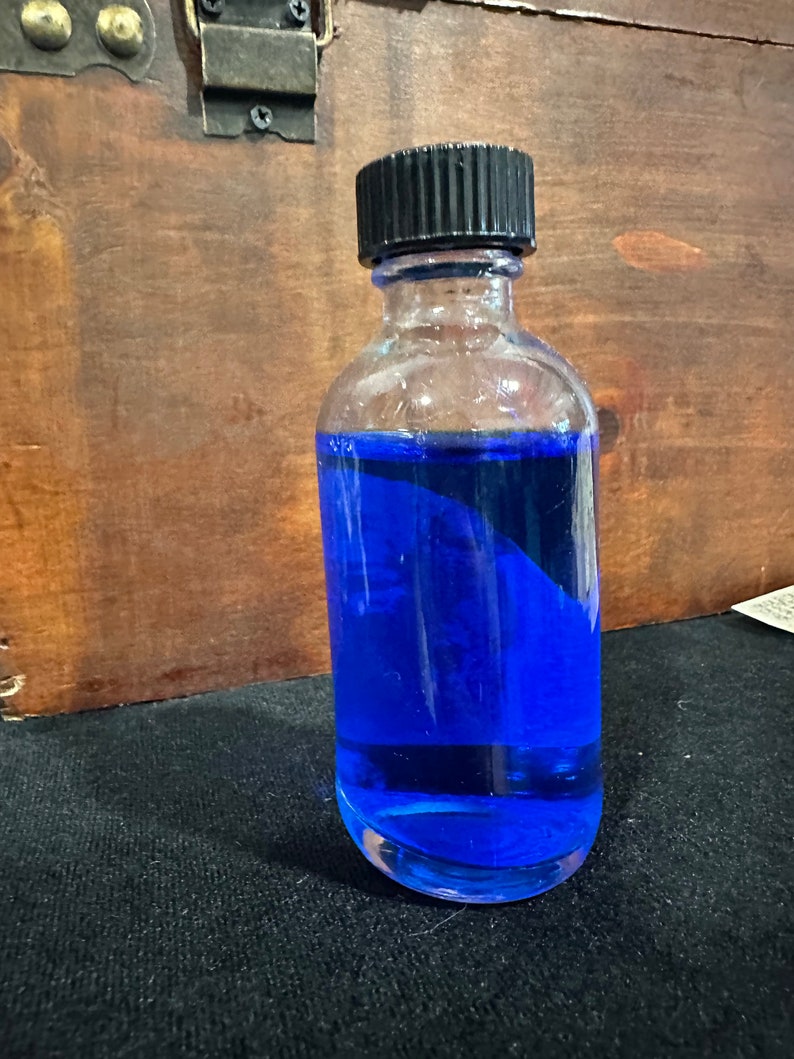 May include: A clear glass bottle with a black screw-on cap filled with a bright blue liquid.