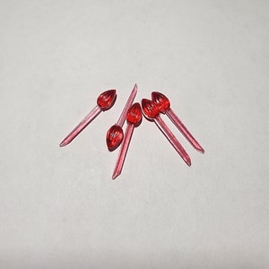 May include: Six red plastic Christmas tree light bulbs with a pointed tip and a clear, translucent stem.