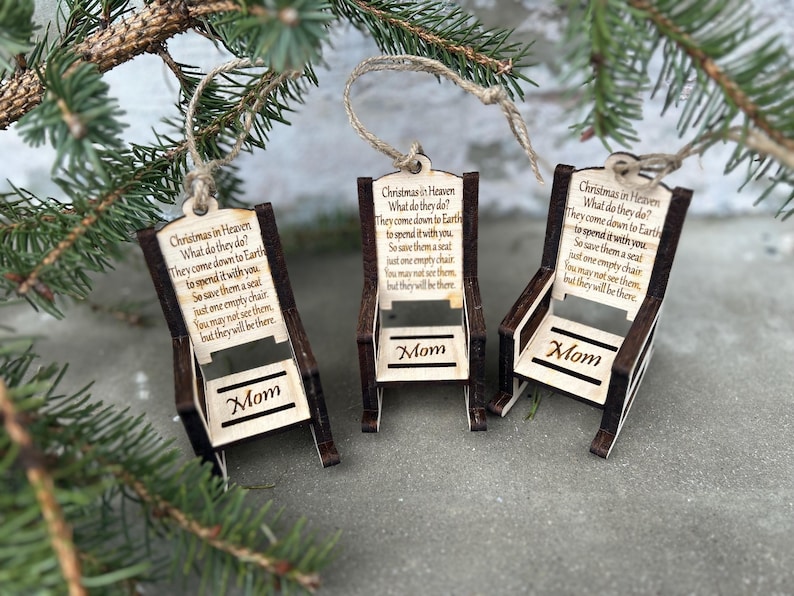 May include: Three wooden Christmas ornaments shaped like chairs, each with a jute string for hanging. The ornaments have the text "Christmas in Heaven" and a poem. The word "Mom" is displayed on each chair.