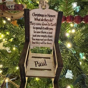 Könnte beinhalten: Weihnachtsbaumschmuck aus Holz in Stuhlform, mit dem Namen "Paul" und einem Gedicht über geliebte Menschen im Himmel. Der Anhänger ist braun und beige, an einer Schnur befestigt, und hängt an einem Weihnachtsbaum.
