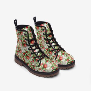 May include: A pair of floral print boots. The boots feature a white background with a pattern of red flowers and green leaves. They have black laces, a black collar, and a brown sole. The boots are designed for everyday wear.