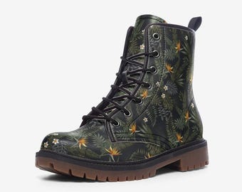 May include: A lace-up ankle boot featuring a dark green background with a repeating pattern of tropical leaves, white flowers, and orange bird of paradise blooms. The boot has black laces, silver-tone eyelets, and a thick, brown lugged rubber sole.
