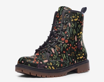 May include: Black combat boots with a floral pattern featuring orange, yellow, and pink flowers, and green leaves. The boots have black laces and a brown sole.