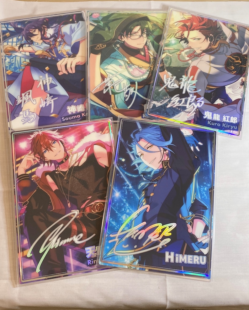 May include: Five holographic cards featuring anime characters with colorful backgrounds and signatures. The characters are dressed in different outfits and have different hairstyles. The cards are all in a clear plastic sleeve.