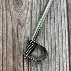May include: A silver metal curtain rod finial with a spiral design.
