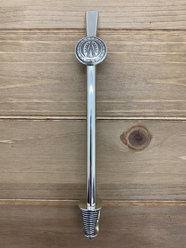 May include: Silver metal straw with a round, decorative top featuring a religious image. The straw has a spring-loaded bottom.