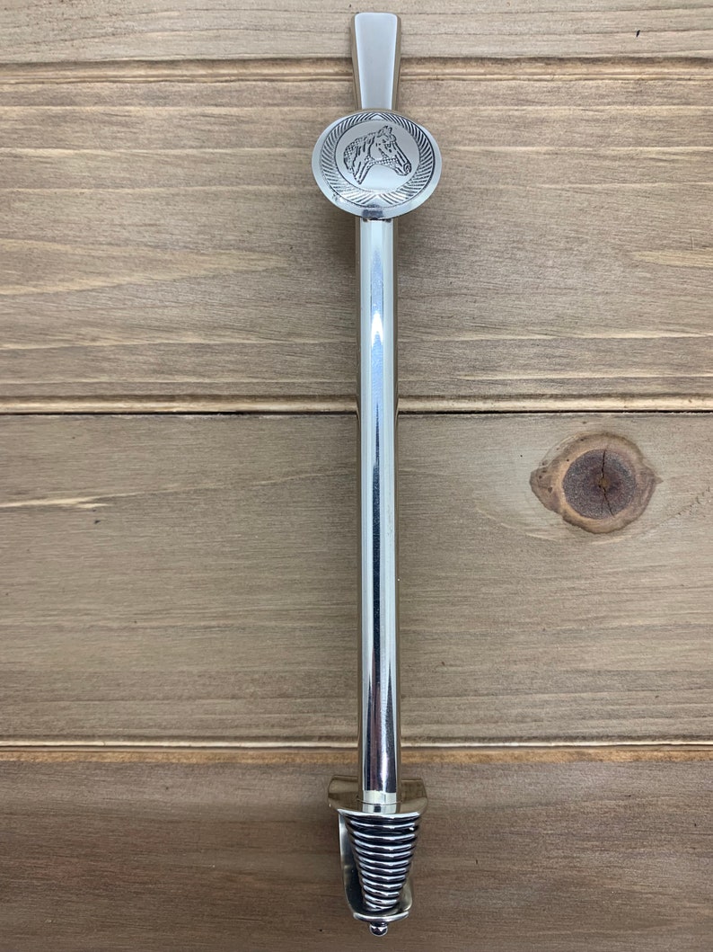 May include: A silver metal door handle with a horse head design on the top and a spiral design on the bottom.