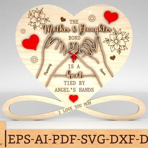 May include: Wooden heart-shaped sign with the text "The Mother & Daughter Bond is a Knot Tied by Angel's Hands" and two hands tied together with a red ribbon. The sign also includes the text "Mommy" and "Anna" and the phrase "I Love You Mom".