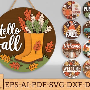 以下が含まれることがあります： 「Hello Fall」の白い文字が入った丸い木製の看板。オレンジ色のブーツと秋の葉、茶色の背景が特徴です。秋をテーマにした丸い看板も表示されています。
