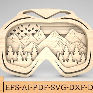 Op de afbeelding: Houten uitsnijding van een paar goggles met een berg- en Amerikaanse vlagontwerp. De goggles zijn gemaakt van hout en hebben een gedetailleerd ontwerp met bergen, bomen en de Amerikaanse vlag.