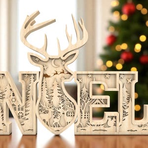 May include: Wooden "NOEL" Christmas decoration with a reindeer silhouette. The letters are intricately cut with festive scenes, including trees, stars, and a sleigh. The decoration is made of light-colored wood and is designed to stand on a flat surface.