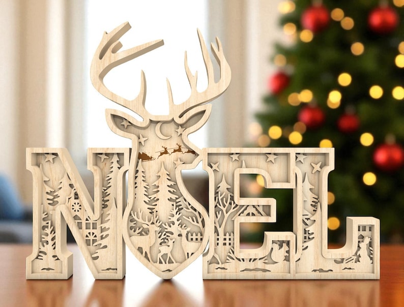 May include: Wooden "NOEL" Christmas decoration with a reindeer silhouette. The letters are intricately cut with festive scenes, including trees, stars, and a sleigh. The decoration is made of light-colored wood and is designed to stand on a flat surface.
