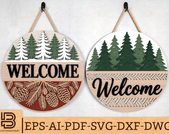May include: Two round wooden welcome signs with a forest theme. One sign has white and green trees, the word "WELCOME", and pine cones. The other sign has green trees and the word "Welcome". Both signs hang from a rope.