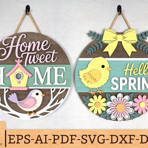 May include: Two circular wooden signs with spring designs. One reads "Home Tweet Home" with a birdhouse and bird. The other says "Hello Spring" with a chick and flowers. Both have rope hangers.