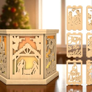 Op de afbeelding: Een houten kerststal met een licht aan de binnenkant. De scène is een zeshoekige doos met uitgesneden ontwerpen van het kerstverhaal. Extra houten uitsparingen van de kerststal zijn inbegrepen.