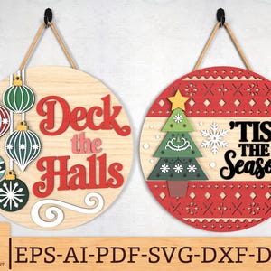 以下が含まれることがあります： 2つの丸い木製のクリスマスサイン。1つはオーナメント付きで「Deck the Halls」と書かれています。もう1つはクリスマスツリーと雪の結晶で「'Tis the Season」と書かれています。どちらも吊り下げ用のロープが付いています。